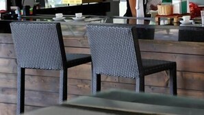 Un café moderne avec une grande fenêtre, un comptoir doté d’une vitrine et deux chaises au premier plan.