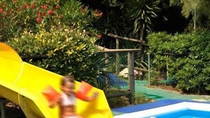 Une piscine avec un toboggan jaune et des requins gonflables.