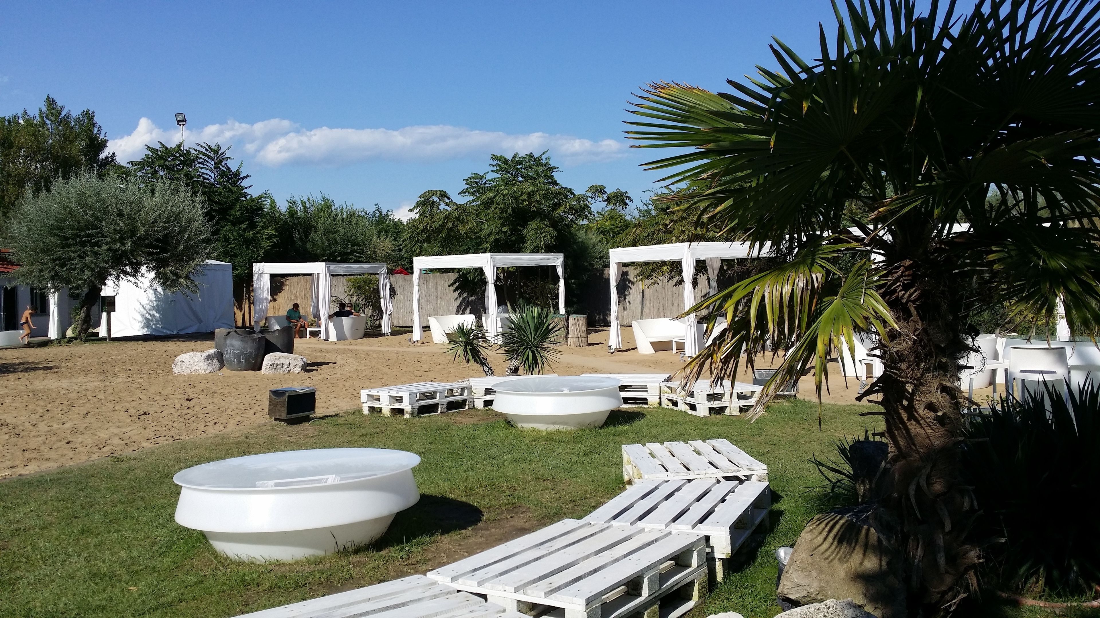A beachside area with white lounge chairs, a large white pool, and covered seating areas.