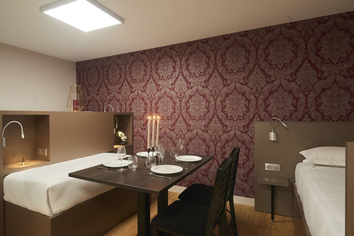 Une chambre d’hôtel compacte comprenant un coin repas, un lit et un petit coin salon.