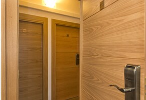 Dos puertas de madera con los números 602 y 613, un picaporte metálico y una lámpara sobre las puertas.