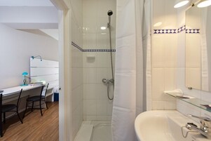 Un baño con ducha, lavamanos y espejo.