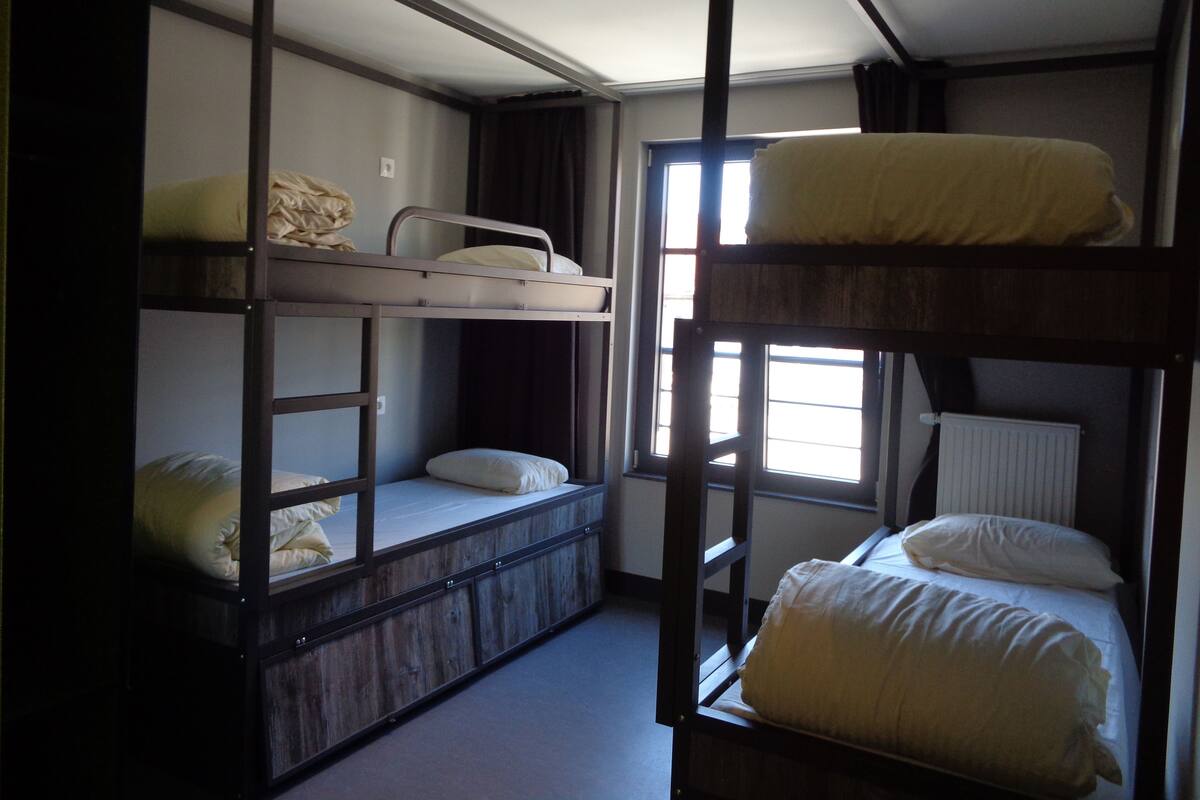 Een slaapkamer met een stapelbed, raam, radiator en deur.
