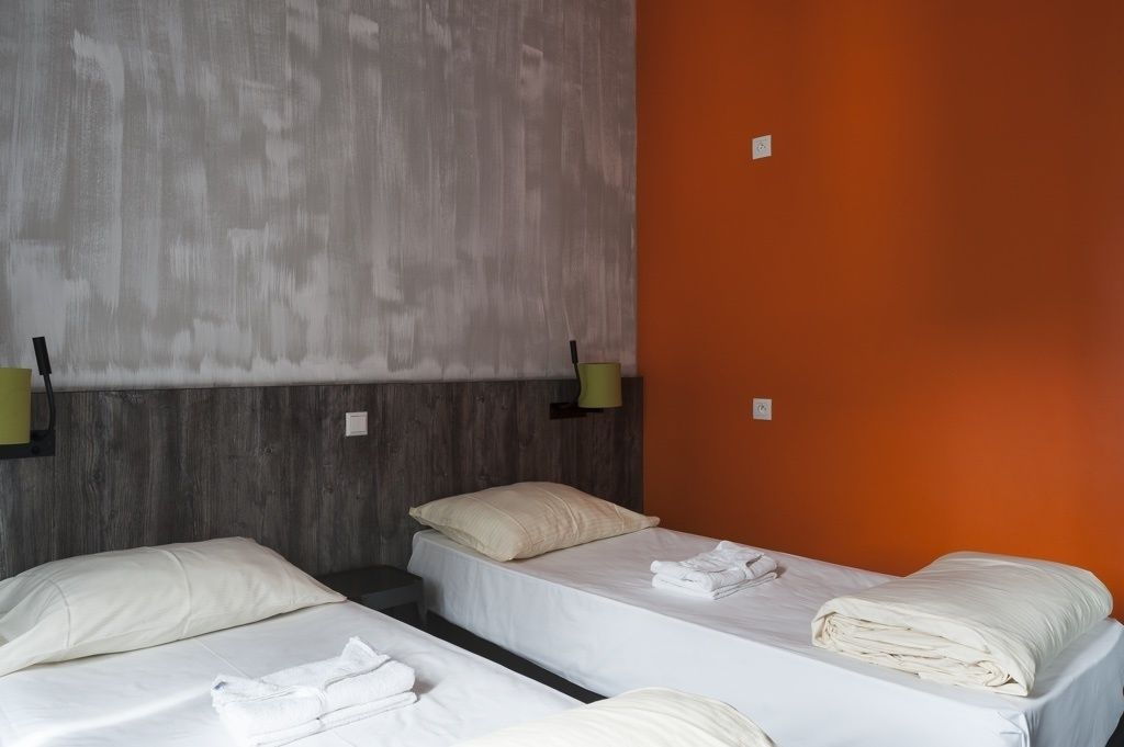 A hotel room with two single beds, each with a pillow and a folded towel.