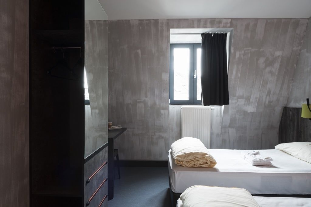 Habitación de hotel con dos camas, un escritorio y una ventana con cortinas.