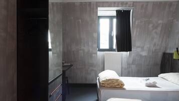 Habitación de hotel con dos camas, un escritorio y una ventana con cortinas.