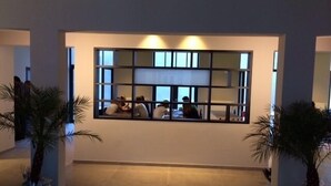 A lobby with a large window, potted plants, and a tiled floor. - BRXXXL5 - Hostel (Brussels)