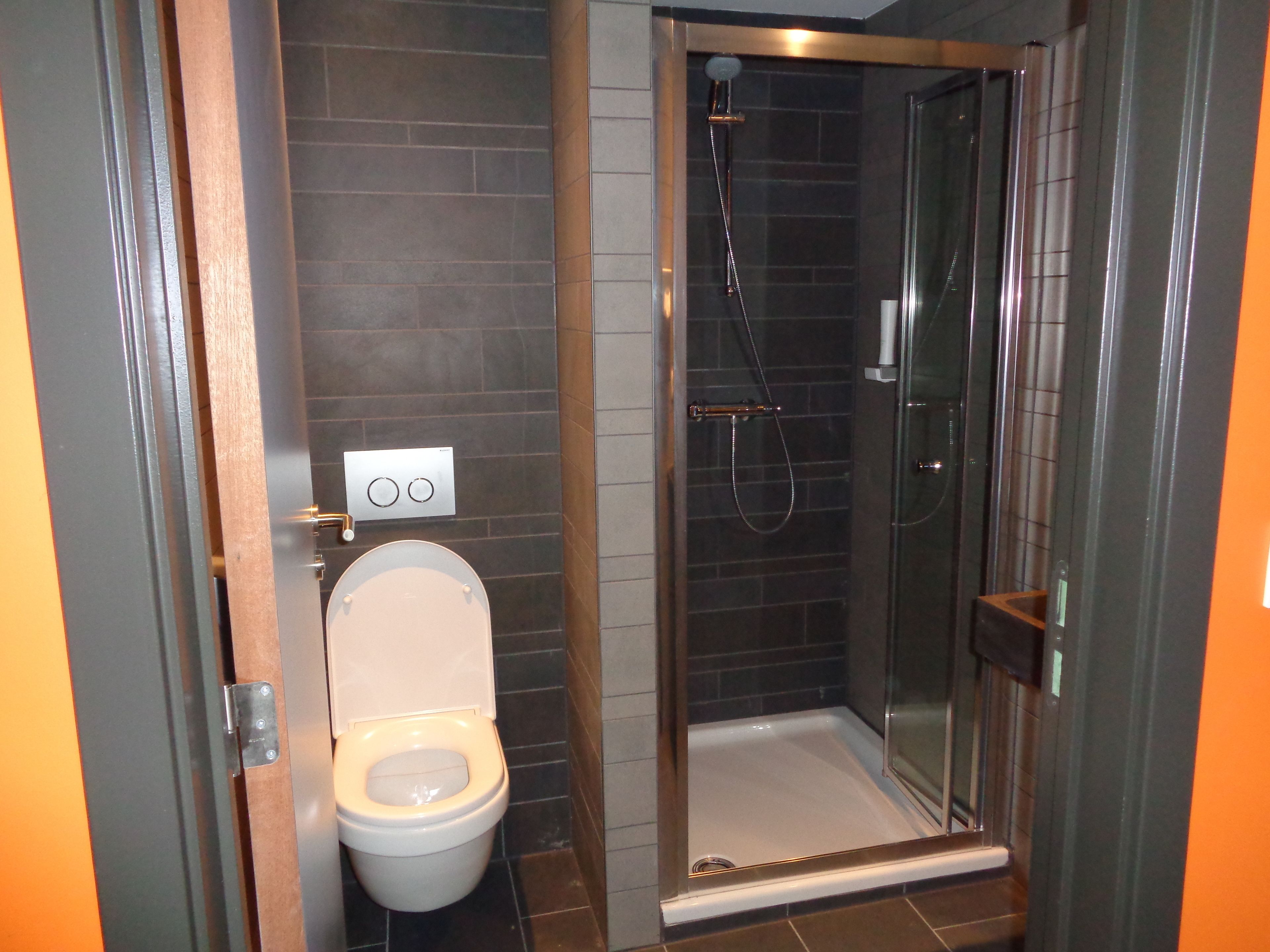 Un baño con inodoro, ducha y cabina de ducha de vidrio.