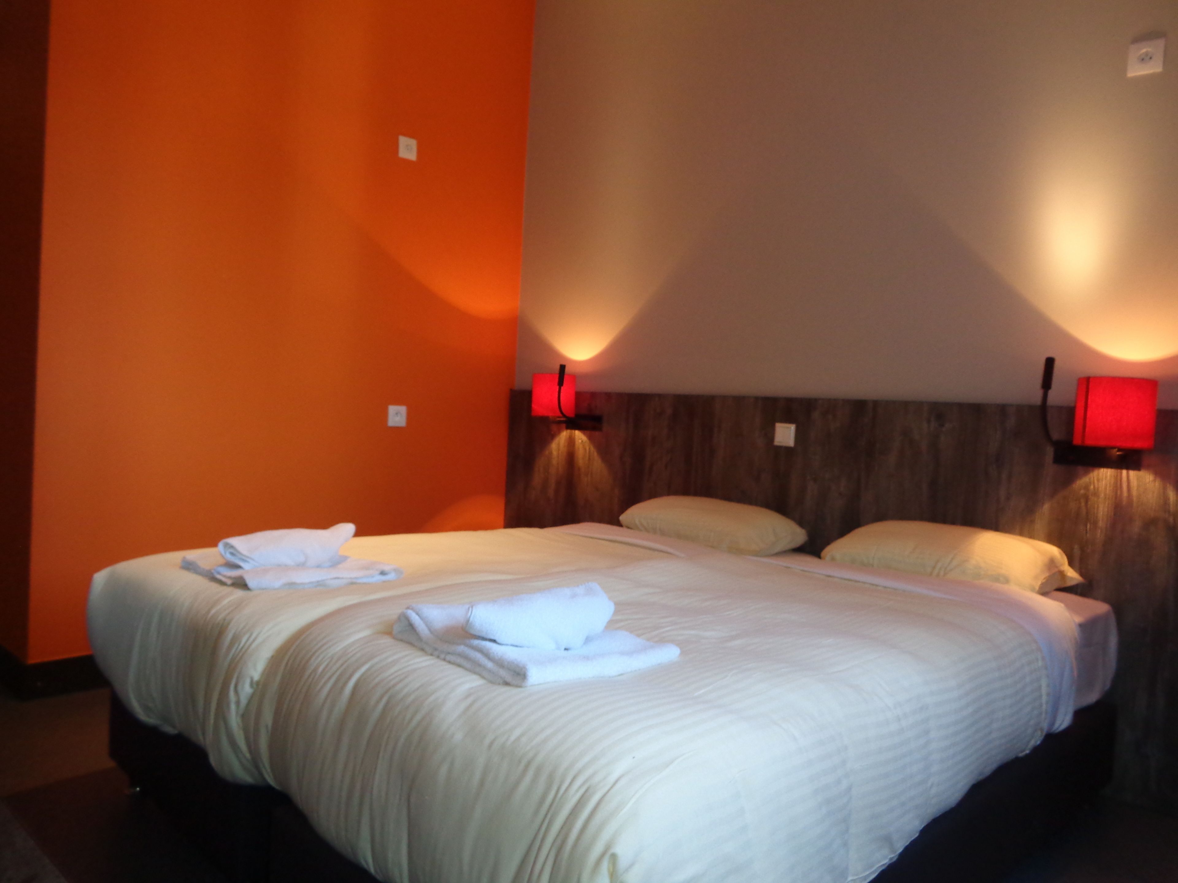 A hotel room with a large bed, two bedside lamps, and a wooden headboard.