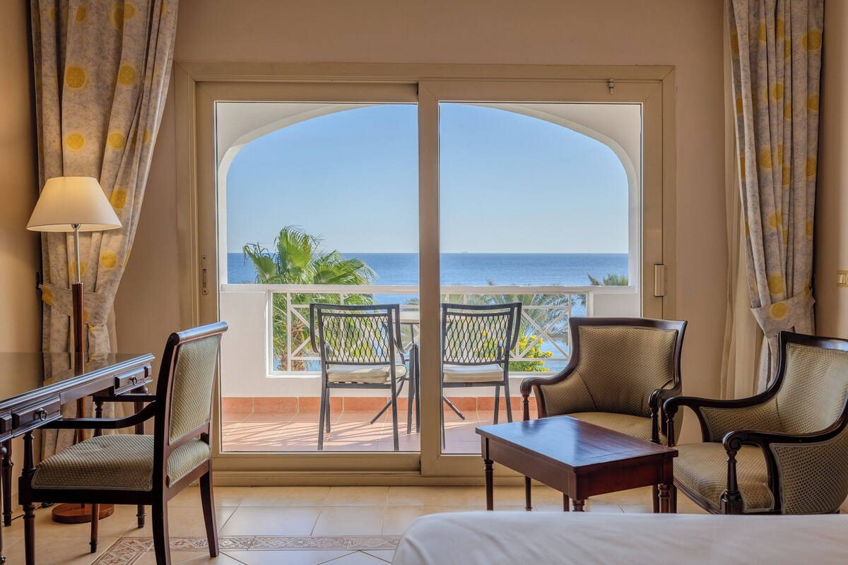 Habitación de hotel con balcón, dos sillas, una mesa y una cama.