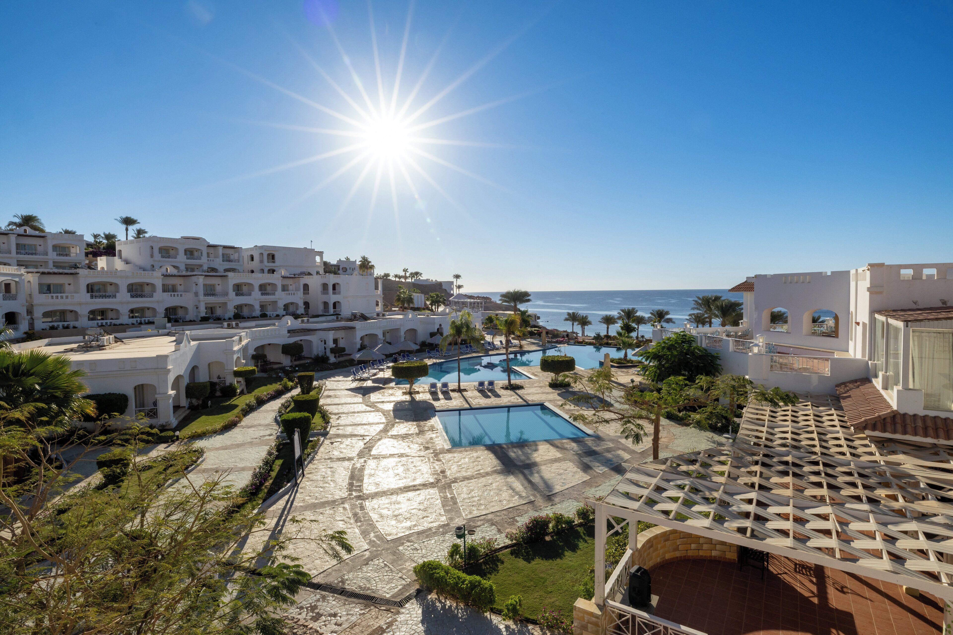 A resort with multiple swimming pools, a clear view of the ocean, and a Mediterranean architectural style.