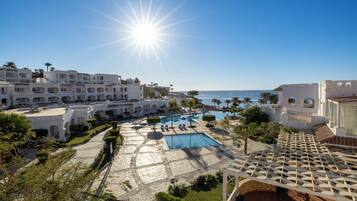 A resort with multiple swimming pools, a clear view of the ocean, and a Mediterranean architectural style.