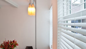 A modern dining area with a white table, black chairs, a vase with flowers, and a hanging light fixture. - Short Stay Maff Apartment (The Hague)
