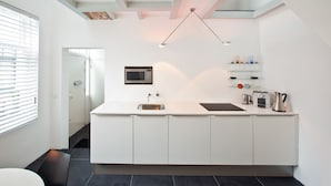 A modern kitchen with white cabinets, a stainless steel sink, a microwave, and a coffee maker. - Short Stay Maff Apartment (The Hague)