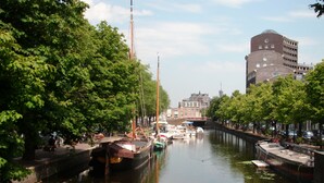 A canal with boats docked, surrounded by trees and buildings. - Short Stay Maff Apartment (The Hague)