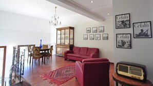 A living room with a red sofa, a wooden cabinet, and a chandelier. - Villa Cerniglia (Cefalù)