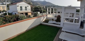 A balcony with artificial grass, a cactus, and a white partition. - Villa Cerniglia (Cefalù)