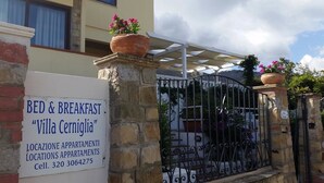 A sign for "Villa Cerniglia" bed & breakfast with a stone wall and metal gate. - Villa Cerniglia (Cefalù)
