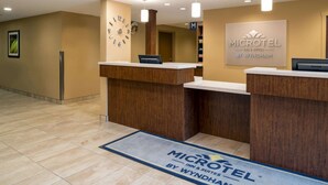 Una zona de recepción con un mostrador de madera, un reloj y un cartel que dice 'MICROTEL INN & SUITES BY WYNDHAM'.