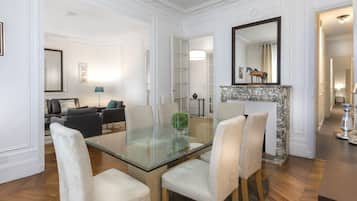 Un comedor con mesa y sillas de vidrio, una chimenea y un espejo en la pared.