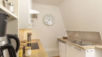 Una cocina moderna con cafetera, frascos y un reloj en la pared.