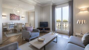 A modern living room with a television, seating area, and large windows with a balcony view.