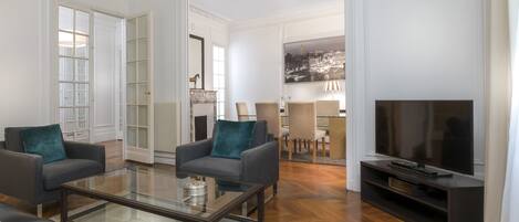 A spacious living room with a large flat-screen TV, two sofas, and a coffee table.