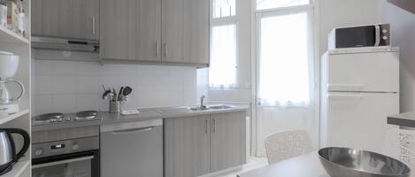 A modern kitchen with grey cabinets, a built-in oven, a microwave, and a sink.