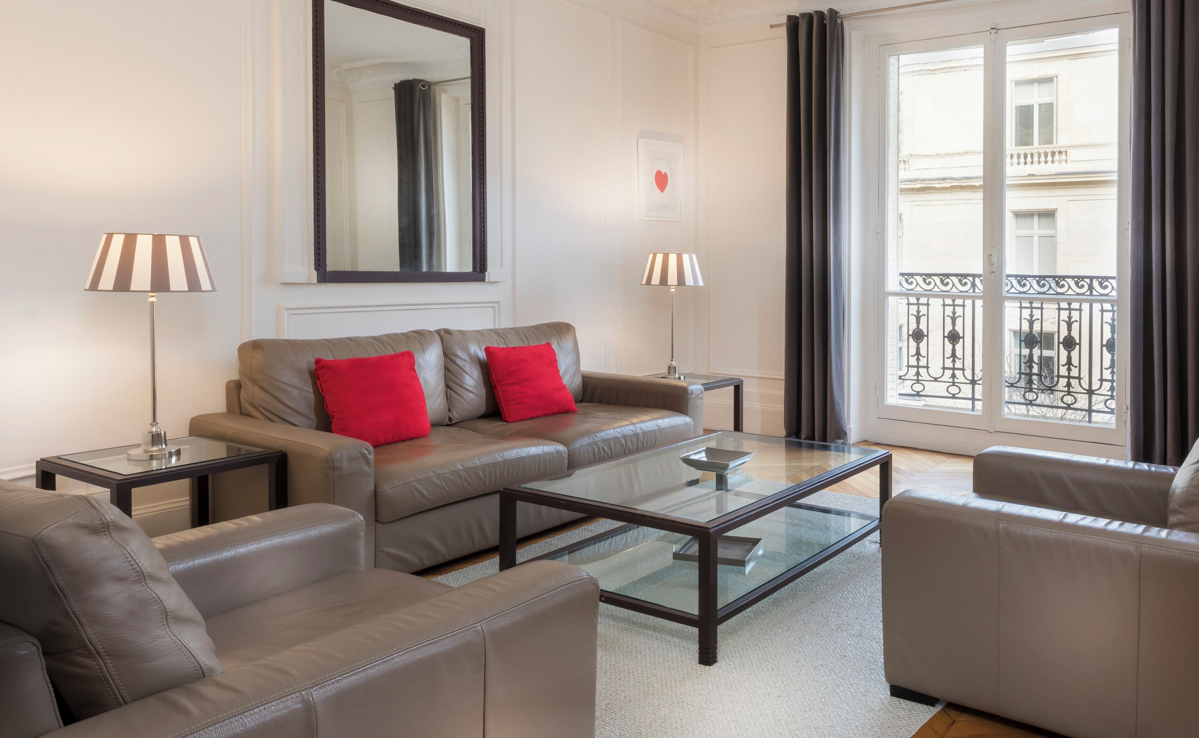 Una sala moderna con un sofá, dos sillones, una mesa de centro de vidrio y dos lámparas.