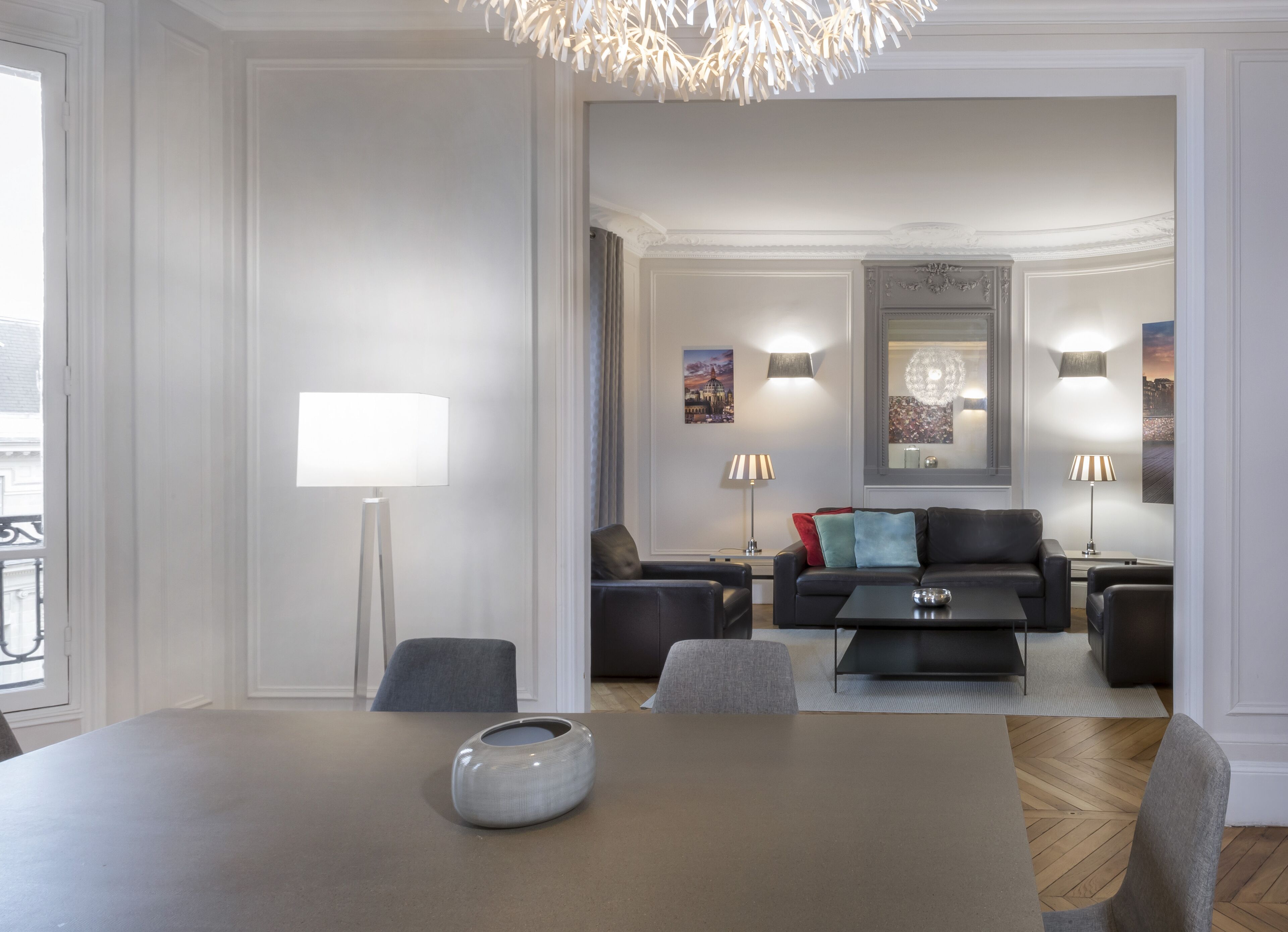 A modern living room with a dining table, sofas, and a chandelier.
