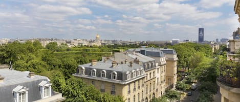 A historic building with classical architecture, surrounded by lush greenery and a clear sky.