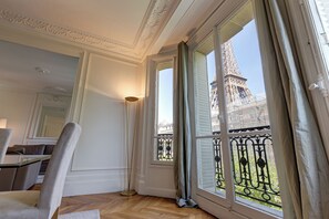 A room with a view of the Eiffel Tower, a wooden floor, a chair, and a lamp. - Résidence Charles Floquet (Paris)