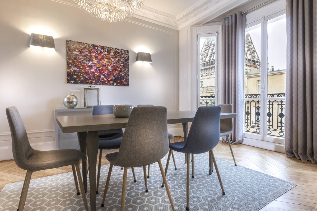 A dining area with a table, chairs, and a patterned rug.