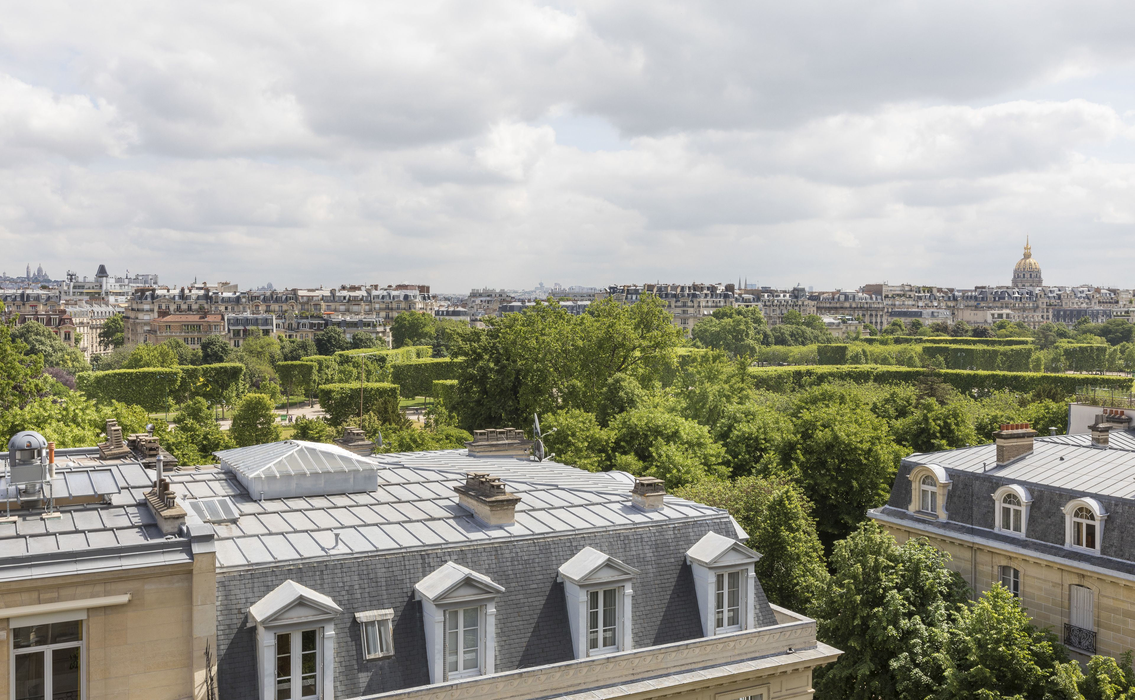 A view of Parisian rooftops with a mix of residential and historical architecture, including a prominent dome in the distance.
