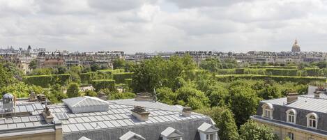 A view of Parisian rooftops with a mix of residential and historical architecture, including a prominent dome in the distance.