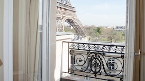 A balcony with a view of the Eiffel Tower, a wrought iron railing, and a window with curtains. - Résidence Charles Floquet (Paris)