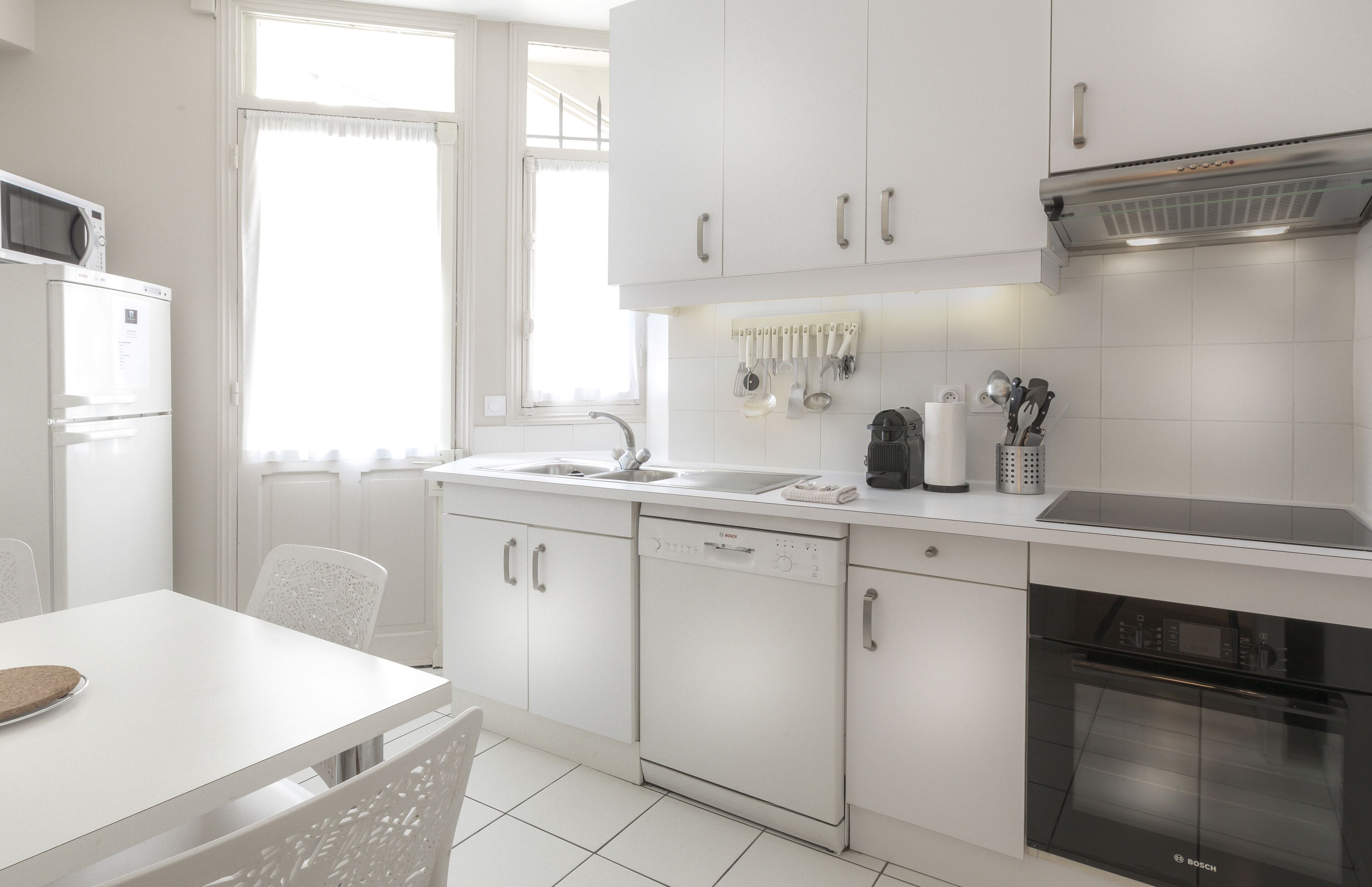 Eine moderne Küche mit weißen Schränken, einem Geschirrspüler von Bosch und einem Backofen von Bosch.