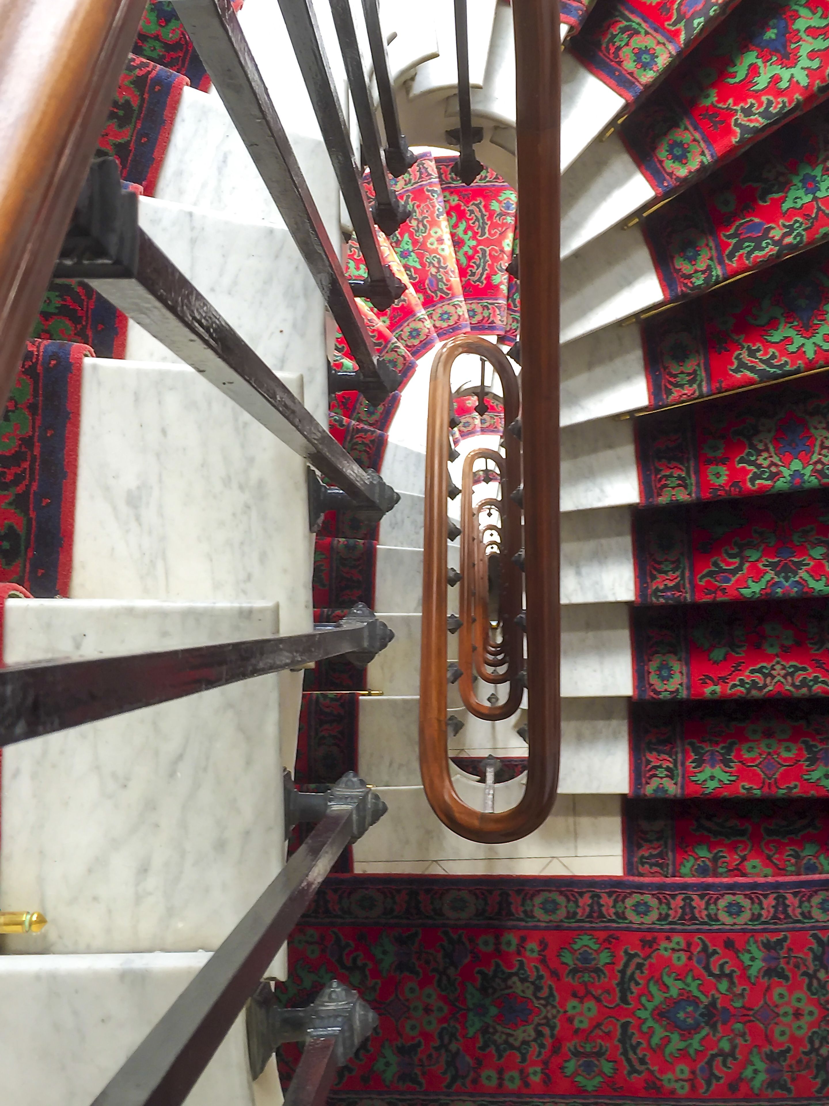 A staircase with marble steps and ornate red carpeted railings.