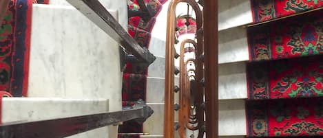 A staircase with marble steps and ornate red carpeted railings.