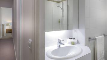 A modern bathroom with a white sink, mirror, and shower.