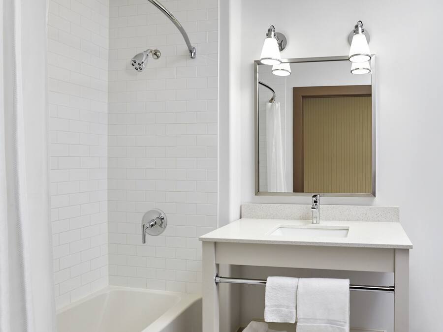 A modern bathroom with a white bathtub, a sink, and a shower with a glass door.