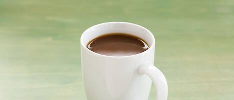 A white mug with a handle on a green surface.