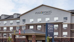 Un hotel de varios pisos con fachada gris y un letrero que dice "FOUR POINTS BY SHERATON".