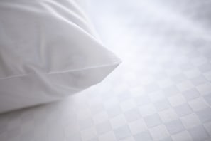 A pillow on a bed with a checkered pattern. - Four Points By Sheraton Regina (Regina)