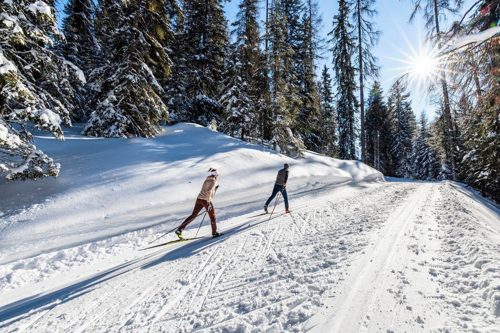 A snowy ski trail with two skiers.