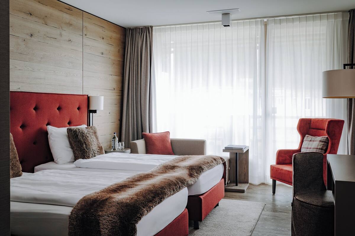Ein Hotelzimmer mit einem großen Bett, einem Sofa, einem Sessel, einem kleinen Tisch und einer Lampe.