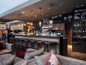 A bar area with stools, a counter, and shelves of bottles.