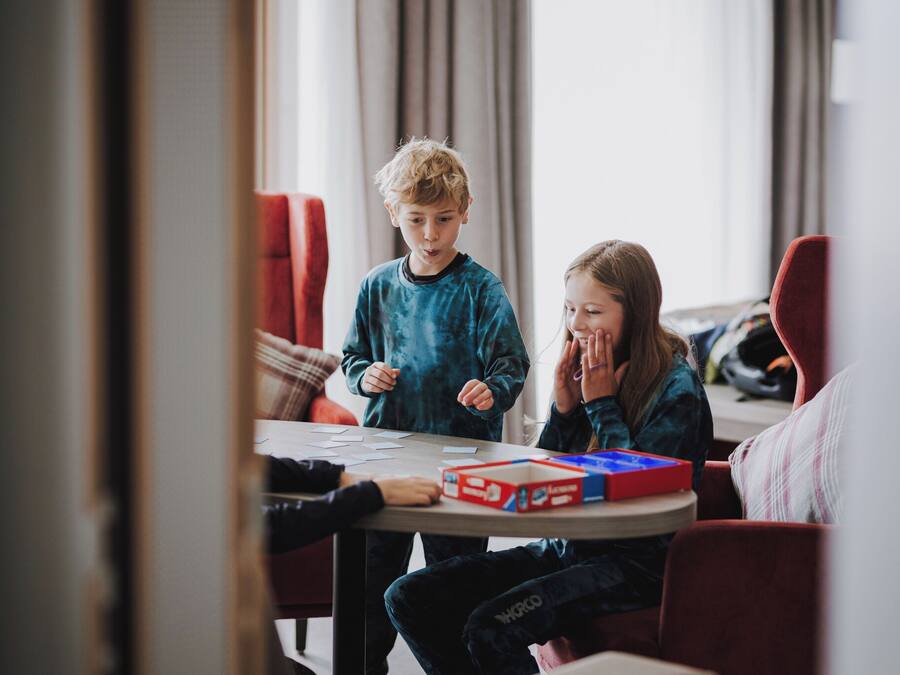Une pièce avec une table ronde, des chaises rouges et un jeu de société.