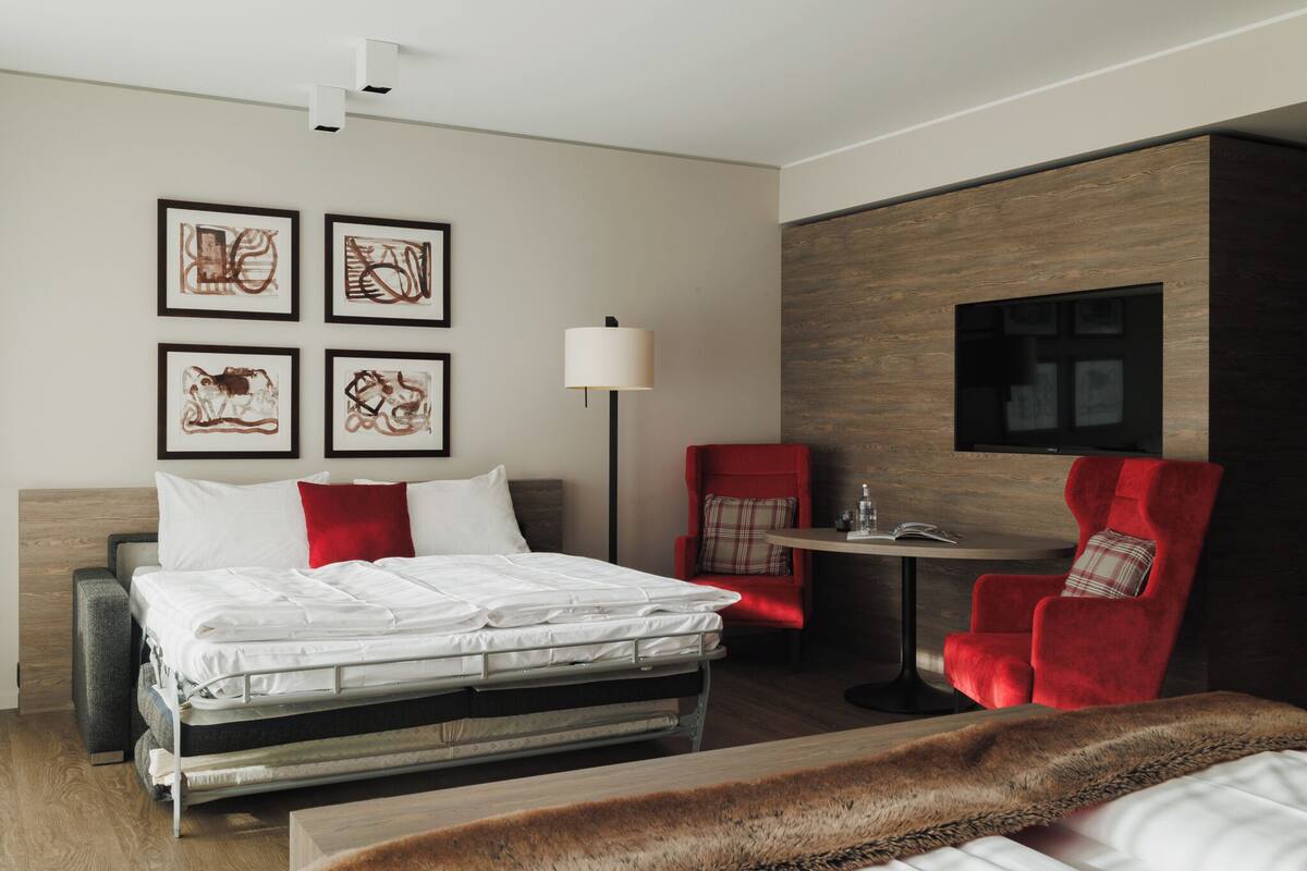 Ein modernes Hotelzimmer mit Bett, Schreibtisch, Stuhl und Bildern an der Wand.