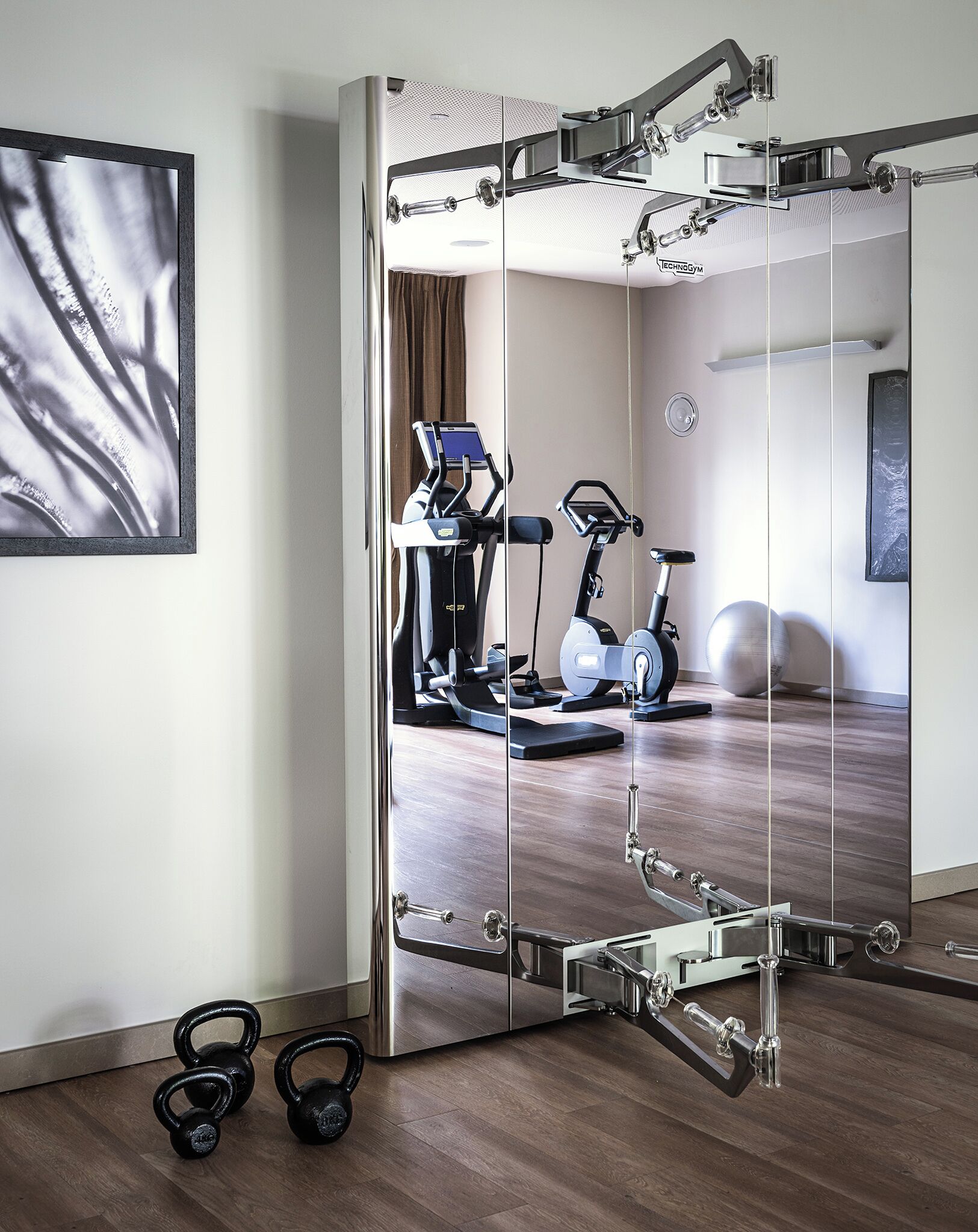 A gym with exercise equipment, a mirror, and kettlebells.